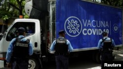 Policías hondureños observan un camión con dosis de vacunas contra el COVID-19 donadas por el gobierno de El Salvador a Honduras, mientras cruza la frontera entre El Salvador y Honduras en Citala, El Salvador, el 13 de mayo de 2021.