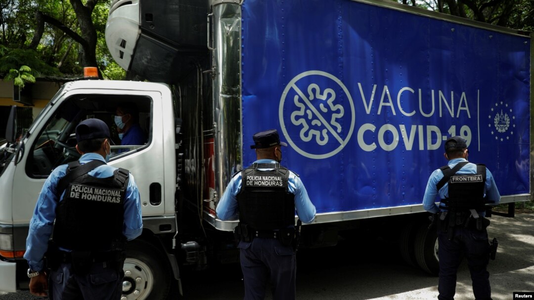Policías hondureños observan un camión con dosis de vacunas contra el COVID-19 donadas por el gobierno de El Salvador a Honduras, mientras cruza la frontera entre El Salvador y Honduras en Citala, El Salvador, el 13 de mayo de 2021.