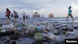 Tourists and local residents disembark a boat coming from nearby Nusa Penida island as plastic trash pollutes the beach in Sanur, Denpasar, Bali, Indonesia April 10, 2018.