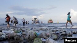 Touris ak moun peyi Endonezi k ap debake yon bato plen ak fatra plastik. Fatra sa yo polye plaj Sanur, nan Denpasar, Vil Bali, nan Endonezi. (Foto: 10 avril 2018).