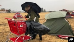 Amy Sheppard packs up items outside her tent in a Walmart parking lot in Chico, Calif., that's been a makeshift campground for people displaced by wildfire, Nov. 21, 2018. Sheppard lost her home in Magalia to the Camp fire. 