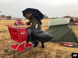 Amy Sheppard packs up items outside her tent in a Walmart parking lot in Chico, Calif., that's been a makeshift campground for people displaced by wildfire, Nov. 21, 2018. Sheppard lost her home in Magalia to the Camp fire.