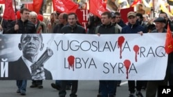 FILE - Russian Communists carry a poster mocking U.S. President Barack Obama during a traditional May Day march in St. Petersburg, Russia, May 1, 2015.