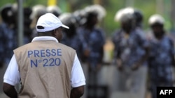 Un journaliste face aux forces de sécurité empêchant une foule de plusieurs centaines de journalistes et de membres du public de manifester devant le Palais des Congrès de Lomé, le 19 février 2013.