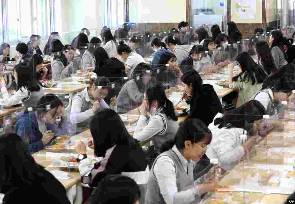 Students eat lunch at tables with protective barriers as a preventative measure against COVID-19, at a high school in Daejeon, South Korea.