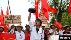 A student carries a monk's alms bowl turned upside down over his head, a Burmese symbol of protest, during a rally against education law in central Yangon, Nov. 17, 2014.