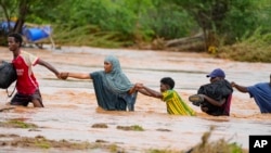 Residents cross a road damaged by El Niño rains in Tula, Tana River county in Kenya on Saturday Nov. 25, 2023.