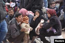 Syrians that evacuated the eastern districts of Aleppo rest while waiting to board buses, in a government-held area in Aleppo, Syria in this handout picture provided by SANA on Nov. 29, 2016.