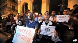 FILE - In this July 1, 2016 photo, Algerian journalists protest against government crackdown in front of the national theater in Algiers. Officials said the independent media "set off alarms" and "darkened” the image of the country. The poster at left reads:"Free Algeria." 