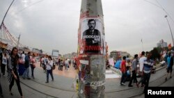 People walk past a poster depicting Turkish Prime Minister Tayyip Erdogan, put up by demonstrators, at Taksim Square in Istanbul June 7, 2013. 