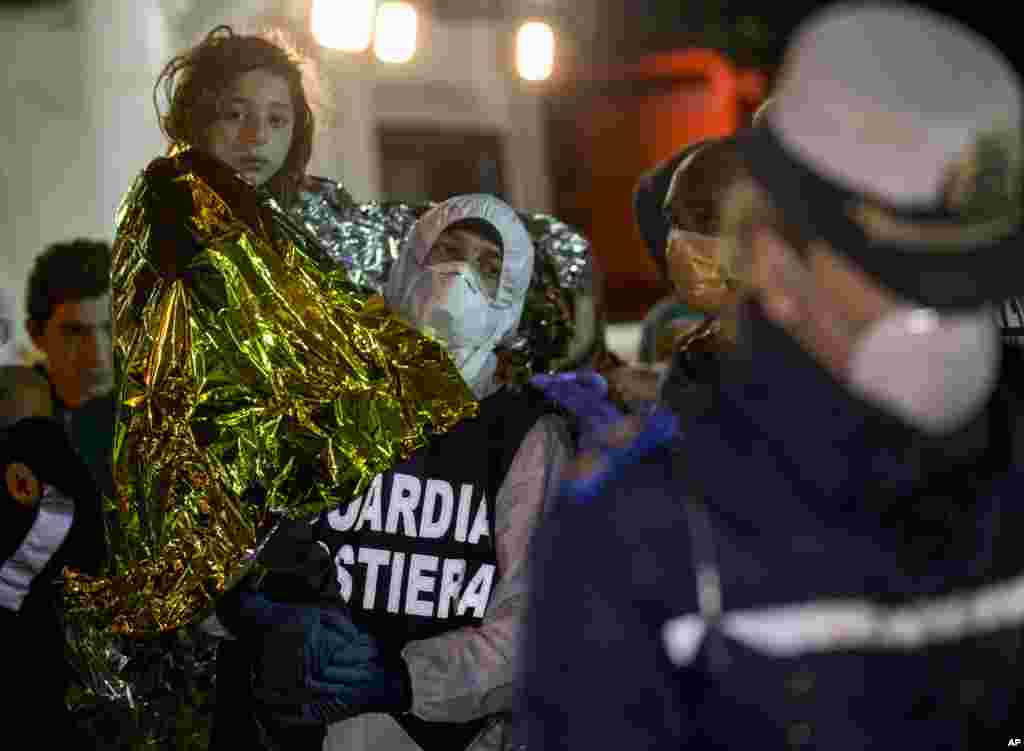 A young girl is carried ashore in the Sicilian harbor of Pozzallo, Italy, early Monday, April 20, 2015.