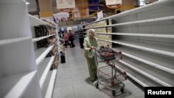 FILE - A shopper looks for food and other staples at a supermarket in Caracas, Venezuela, July 25, 2017. The country's dire political and economic straits are in focus during the UN General Assembly. 