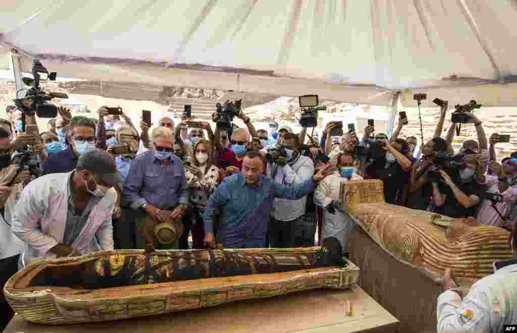 Egyptian Minister of Tourism and Antiquities Khaled Al-Anani (L), and Mustafa Waziri (R), Secretary General of the Supreme Council of Antiquities unveil the mummy inside a sarcophagus excavated at the Saqqara necropolis, south of the capital Cairo. The excavation resulted in the discovery of a deep burial well with more than 59 human coffins closed for more than 2,500 years.