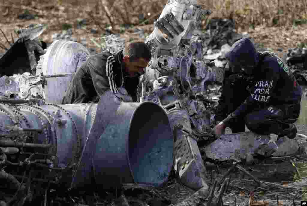 Local citizens collect parts of a downed Ukrainian military helicopter near a small town Raigorodok, outside Slovyansk, Ukraine, Tuesday, May 6, 2014. The helicopter was forced to make an emergency landing Monday during intense fighting in Slovyansk and was later destroyed by Ukrainian troops, who sought to ensure it did not fall into the hands of insurgent forces. (AP Photo/Darko Vojinovic)