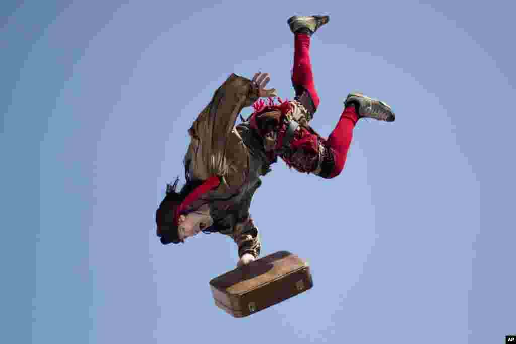 Seorang pemain akrobat melompat dari atas gedung sekolah untuk menghibur anak-anak migran asing dalam perayaan festival Purim di Tel Aviv, Israel.