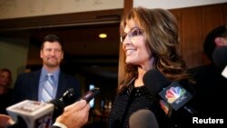 FILE - Former Republican governor of Alaska Sarah Palin speaks to members of the media as her husband Todd looks on before an event in Asheville, North Carolina, Nov. 7, 2013. 