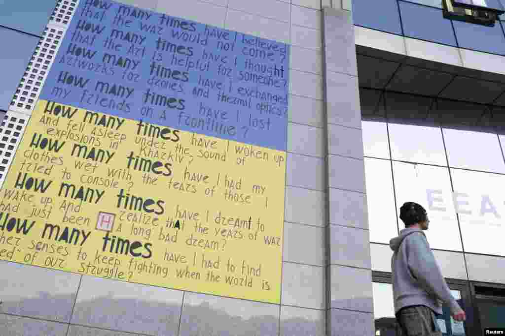 Seorang pria berjalan di samping poster pro-Ukraina di luar kantor pusat Layanan Aksi Eksternal Eropa (EEAS), di Brussel, Belgia. (Reuters)&nbsp;