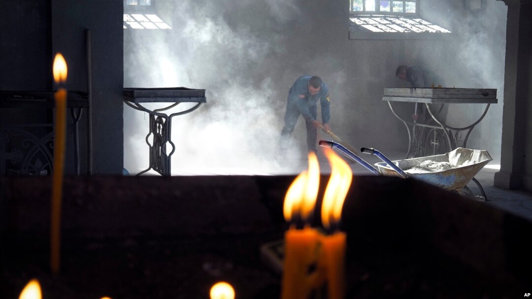 Church workers sweep the dust in the Holy Savior Cathedral, damaged by shelling by Azerbaijan's artillery during a military conflict in Shushi, the separatist region of Nagorno-Karabakh, Saturday, Oct. 24, 2020. The heavy shelling forced residents…