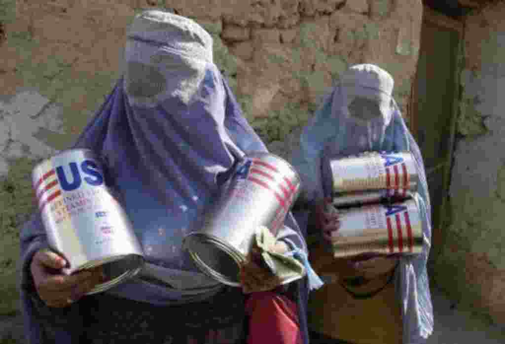 Afghan widows carry out cans of cooking oil from the United Nations World Food Program bakery in Kabul, Afghanistan, Wednesday, Nov. 21, 2001. About 350 widows, identified as the most vulnerable group in the city, received two cans of oil and two sacks of