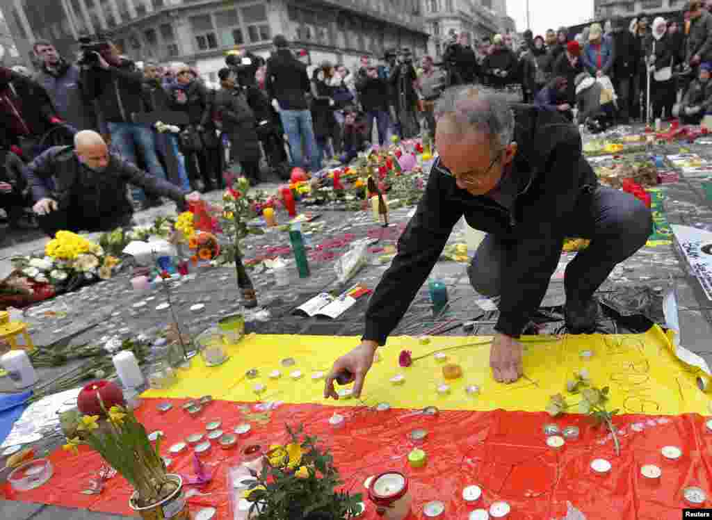 A man places a candle on a street memorial following Tuesday's bomb attacks in Brussels, March 23, 2016. 