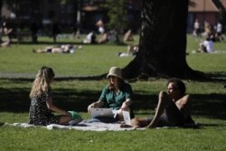 People sit in the sunshine in London Fields, north east London, May 20, 2020.
