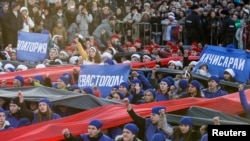 Performers hold banners with names of Crimean cities during celebrations marking the first anniversary of Russia's annexation of Ukraine's Black Sea peninsula of Crimea, in central Simferopol, March 16, 2015. The placards read (L-R), "Yevpatoriya," "Sevastopol" and "Bakhchisaray."