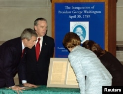 FILE -- Archivist John Carlin with President George W. Bush (L) and Laura Bush as they view George Washington's Inauguration speech at the National Archives, Jan. 19, 2005.