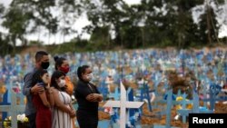 Famille brésilienne au cimetière Parque Taruma à Manaus, où de nombreuses personnes décédées de la maladie COVID-19 ont été enterrées, Brésil, 26 mai 2020. (REUTERS/Bruno Kelly)