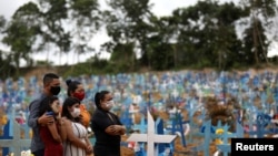 Relatives are seen during a mass burial of people who passed away due to the coronavirus disease, at the Parque Taruma cemetery in Manaus, Brazil.