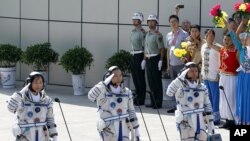 China's astronauts from left Liu Yang, Jing Haipeng and Liu Wang salute before they depart for the Shenzhou 9 spacecraft rocket launch pad at the Jiuquan Satellite Launch Center in Jiuquan, China, Saturday, June 16, 2012.