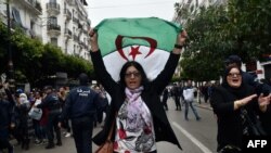 An Algerian woman waves a national flag as she takes part in an anti-government demonstration in the capital Algiers on March 14, 2020.