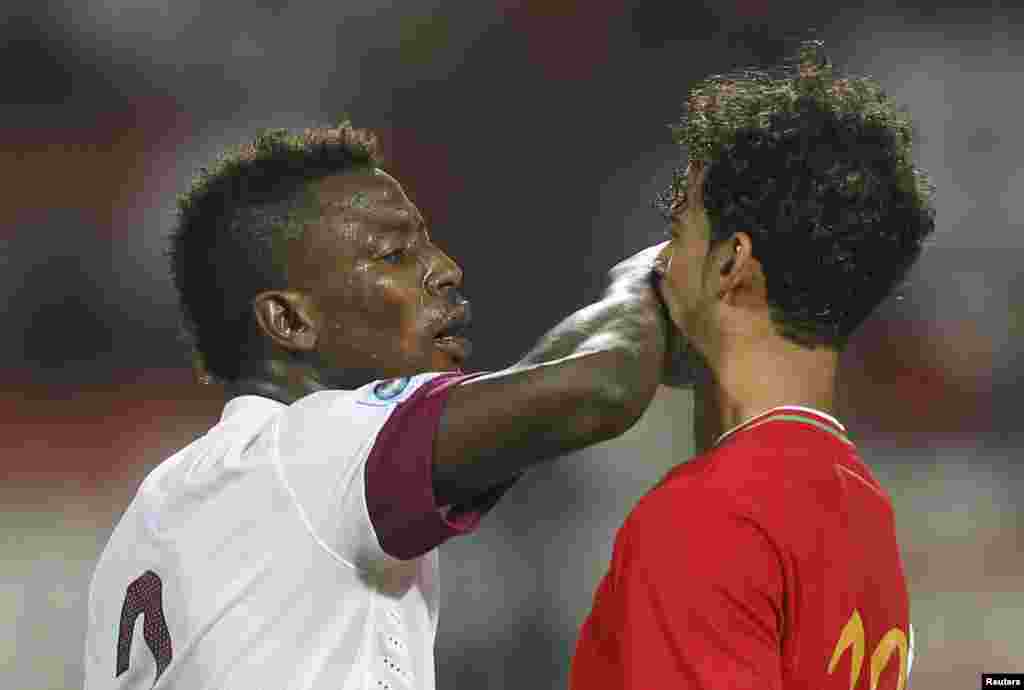 Qatar's Kasola Mohammed (L) confronts Oman's Ahmed Mubarak al Hahaijri during their Gulf Cup tournament soccer match at Isa Sports City in Isa Town, Bahrain.