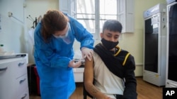 Una trabajadora de salud administra la vacuna Pfizer para COVID-19 a un joven en Montevideo, Uruguay, el miércoles 9 de junio de 2021. Uruguay comenzó a vacunar a jóvenes de entre 12 y 17 años (AP Photo / Matilde Campodonico)