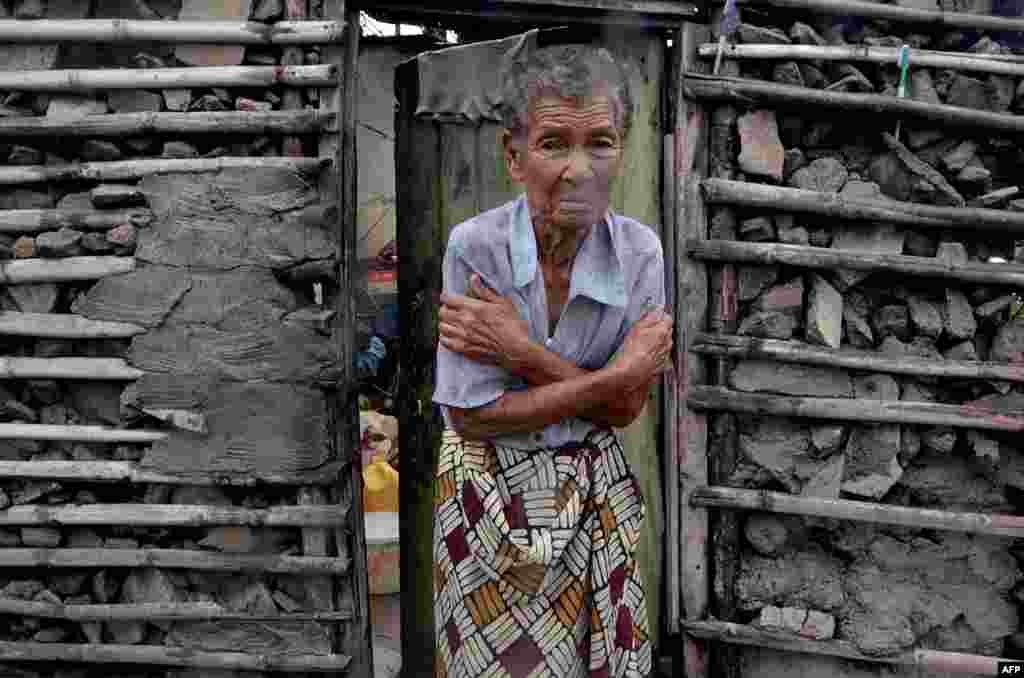 A shivering displaced woman stands in the doorframe of a house in Beira, Mozambique. More than 1,000 people are feared dead in a cyclone that smashed into the country last week.