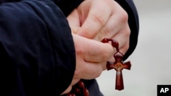 FILE - A man holds rosary beads as he prays for Pope Francis in front of the Agostino Gemelli Polyclinic, where the Pontiff has been hospitalized since Feb. 14, in Rome, Feb. 26, 2025.