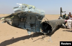 FILE - Men inspect the wreckage of a Russian helicopter that had been shot down in the north of Syria's rebel-held Idlib province, Syria, Aug. 1, 2016.