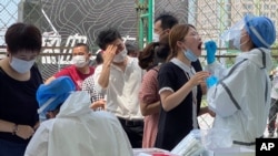 Residents line up to get tested at a coronavirus testing center set up outside a sports facility in Beijing, Tuesday, June 16, 2020.