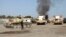 Smoke is seen rising from the Brigade Qaqaa headquarters, a former Libyan Army camp known as Camp 7 April, behind members of the Libya Shield, following clashes between rival militias at the Sawani road district in Tripoli, Aug. 24, 2014. 