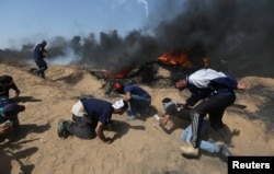 FILE - Palestinian demonstrators take cover from Israeli gunfire during a protest marking Jerusalem Day at the Israel-Gaza border in the southern Gaza Strip, June 8, 2018.
