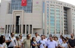 FILE - Journalists are seen gathered outside a court building to support a colleague who was detained in connection with the investigation launched into a failed coup attempt in Turkey, in Istanbul, July 27, 2016.