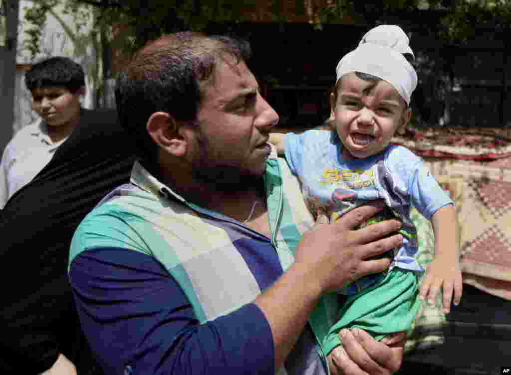 Ali Arar holds his one-year-old wounded son, Aqeel Ali, at the scene of a car bomb attack in the Sadr City neighborhood in Baghdad, May 16, 2013.