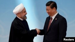 Presiden Iran Hassan Rouhani (kiri) berjabat tangan dengan Presiden China Xi Jinping pada konferensi di Shanghai, 21 Mei 2014 (foto: dok). Kedua pemimpin dijadwalkan bertemu di China 9 Juni mendatang. 