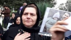 Farangis Mazloum, mother of jailed Iranian dissident Soheil Arabi, appears in this undated photo shared on social media, holding a photo of Arabi and his daughter while campaigning for his release.