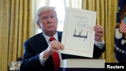 川普总统展示他签名的减税法案