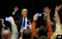 Republican presidential candidate Donald Trump waves to supporters as he arrives at a campaign rally at Clinton Middle School in Clinton, Iowa, Jan. 30, 2016.