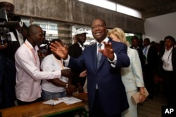 Ivory Coast’s President Alassane Ouattara arrives inside a polling station to cast his ballot during elections in Abidjan, Oct. 25, 2015.