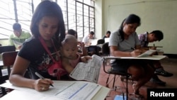13일 필리핀 마닐라의 한 학교에 설치된 투표소에서 투표용지에 기표하는 유권자들.