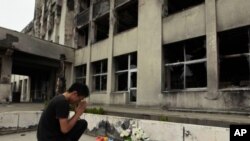 Yuki Omori, 23, prays at a makeshift shrine at Kadowaki Elementary School in Ishinomaki, northeastern Japan, September 11, 2011, six months after the March 11 earthquake.