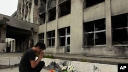 Yuki Omori, 23, prays at a makeshift shrine at Kadowaki Elementary School in Ishinomaki, northeastern Japan, September 11, 2011, six months after the March 11 earthquake.