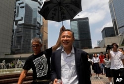 Pemimpin Occupy Central Benny Tai, tengah, ditemani seorang pendukung yang mengangkat payung saat meninggalkan Pengadilan Tinggi di Hong Kong, 15 Agustus 2019. (Foto: AP)